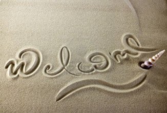 11453058-simple-welcome-message-in-the-sand-with-a-shell